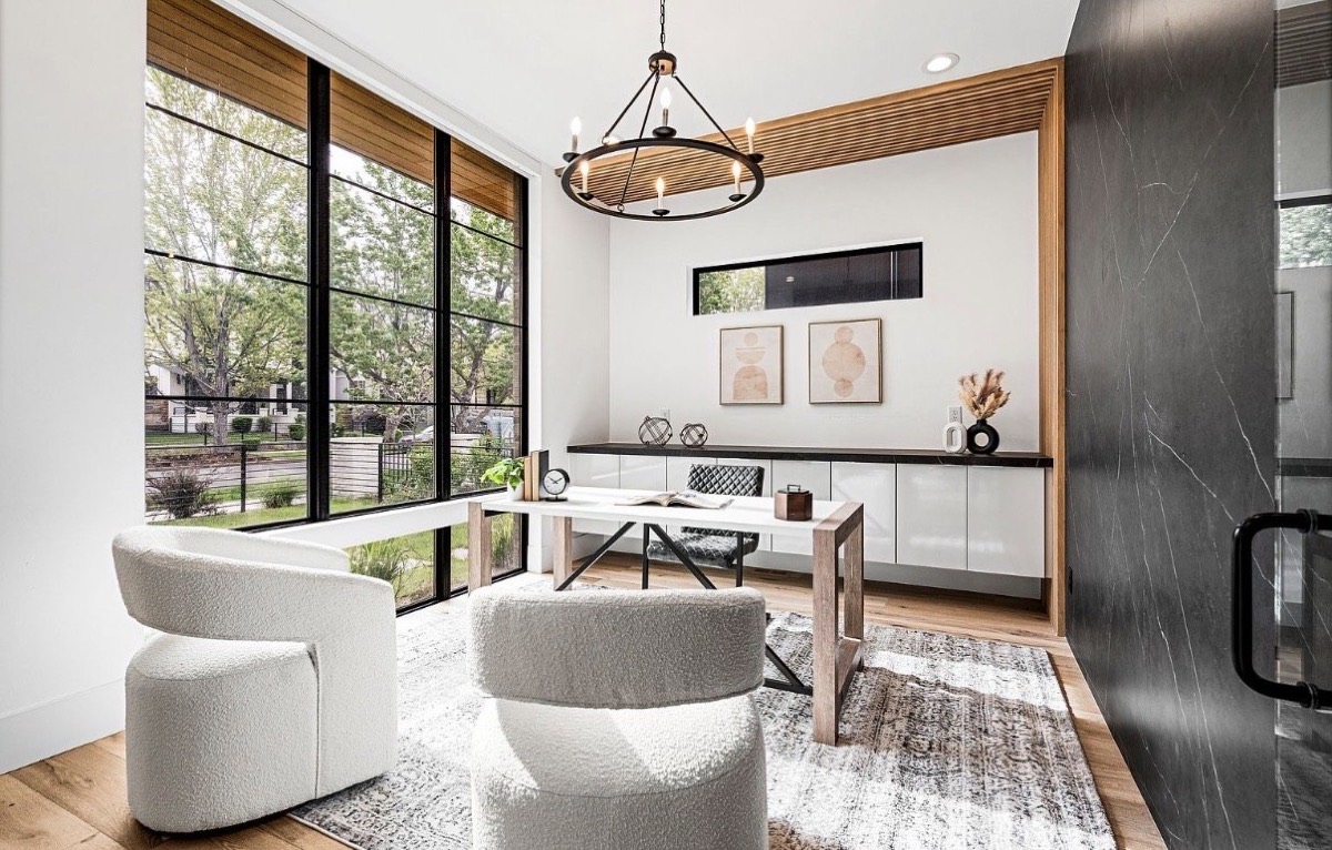 Light-filled home office with floor-to-ceiling black steel windows, iron chandelier and cream boucle swivel chairs