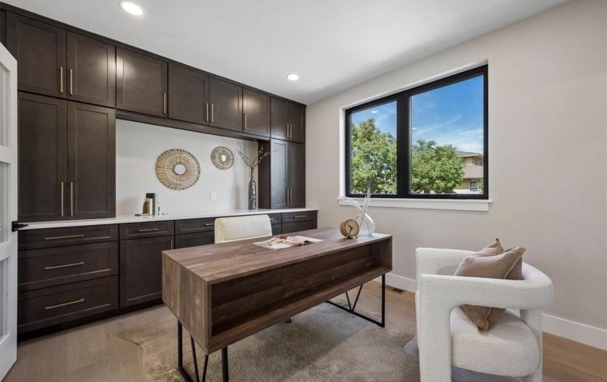 Home office with espresso built-in cabinetry, a walnut desk and white boucle accent chair