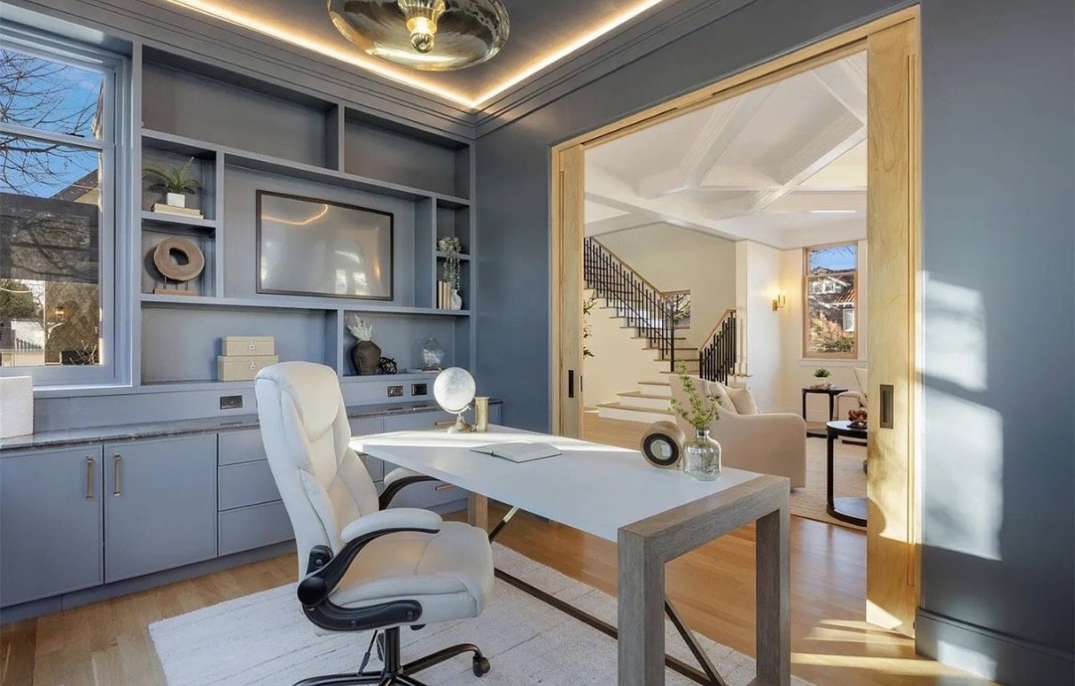 Home office with slate blue built-ins, a white desk and oak pocket doors to the foyer