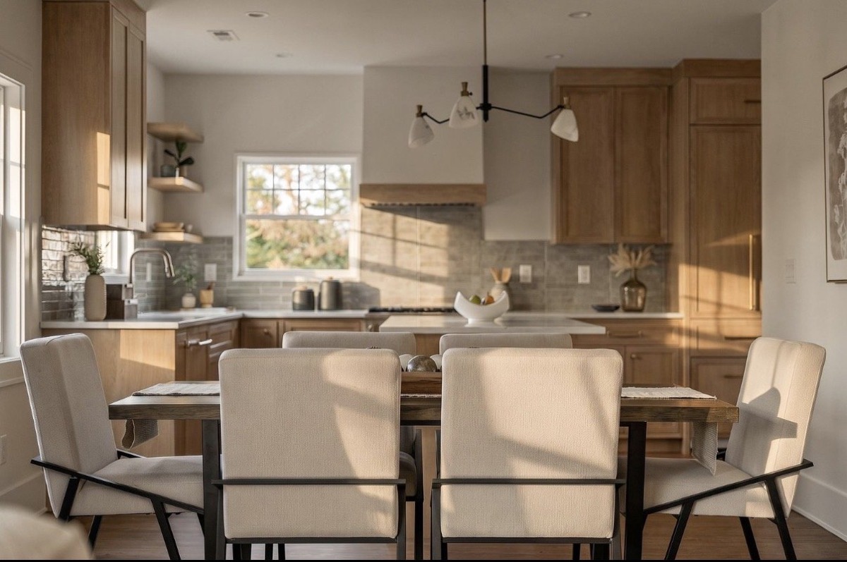 Dining table with cream upholstered chairs set in front of a white oak kitchen with open shelving
