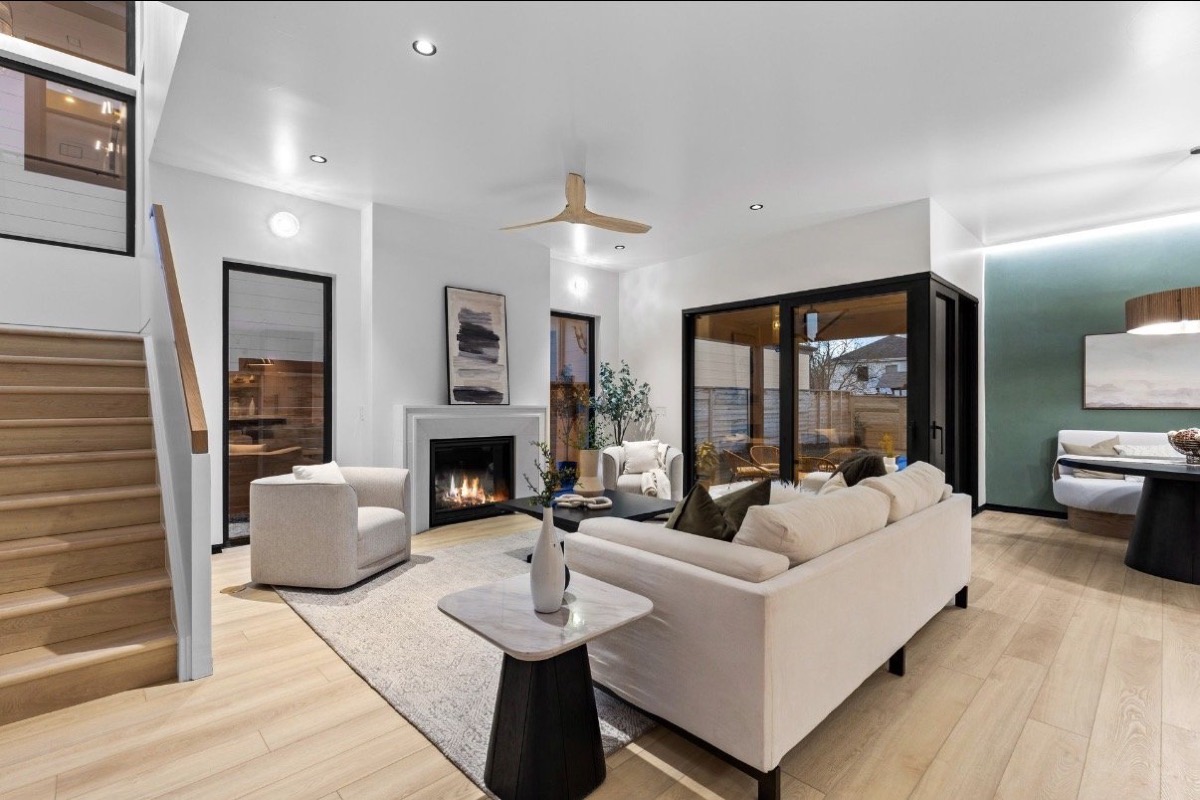 Modern living room with a white fireplace, light oak floors, cream sofa and sage green accent wall