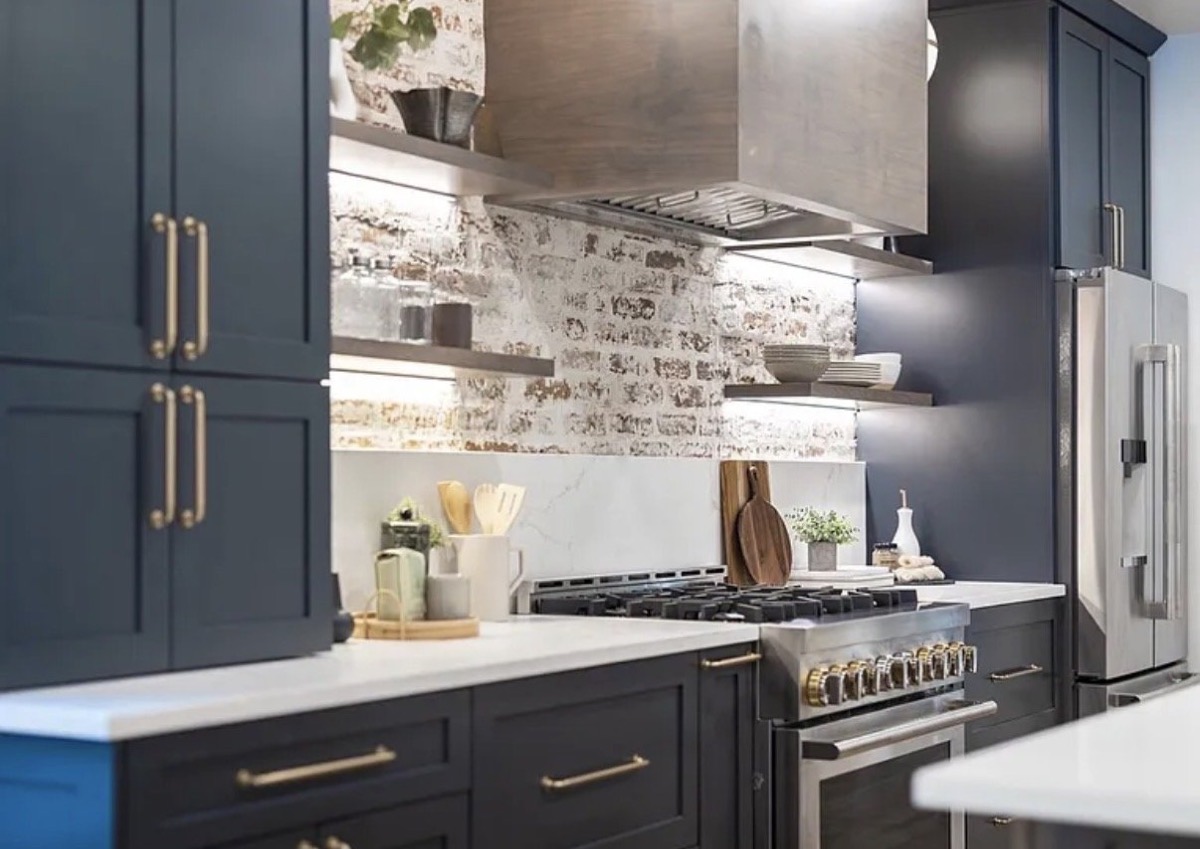 Navy kitchen with whitewashed brick backsplash, open floating shelves and brass hardware