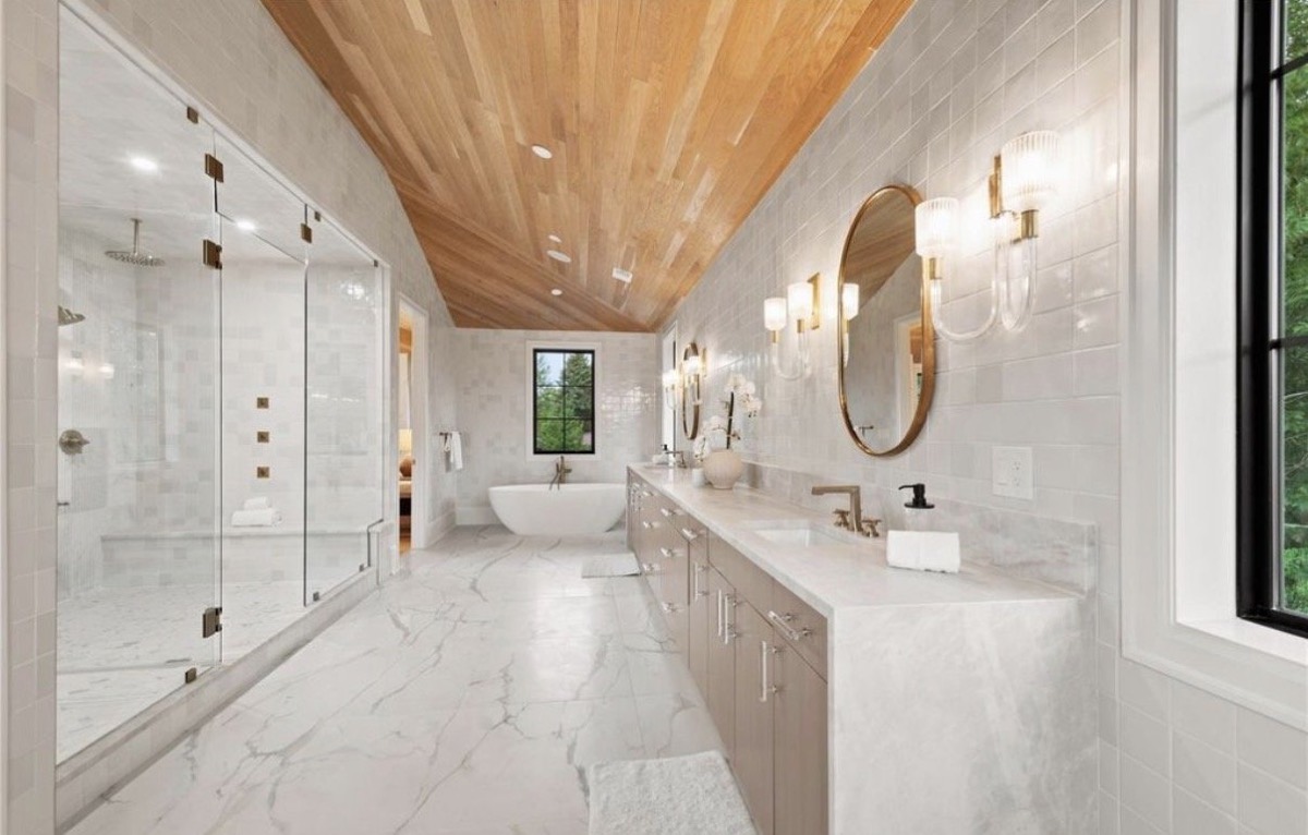 Primary bathroom with a vaulted wood plank ceiling, freestanding tub, marble tile and walk-in glass shower